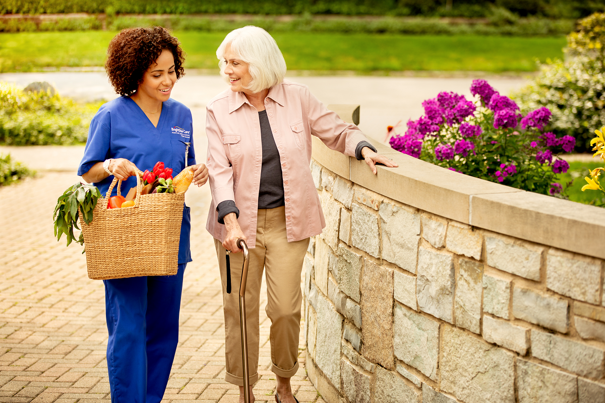 brightstar care caregiver walking with client outside next to flowers