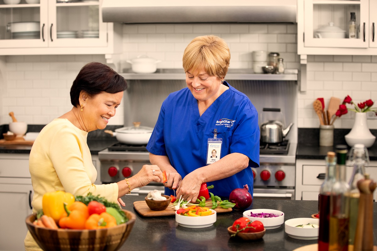 BrightStar Care nurse assisting patient with cooking. 