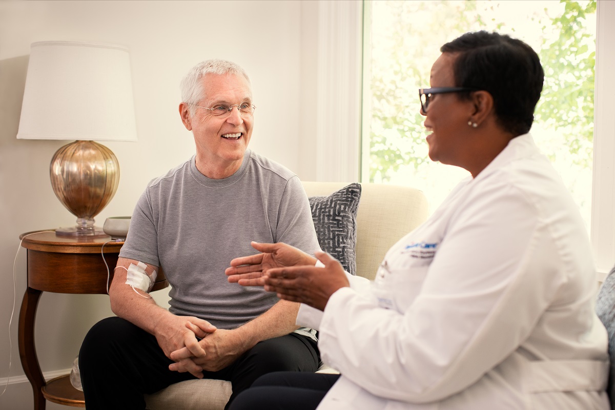 A BrightStar Care caregiver discusses treatment with her client while they sit in a living room.